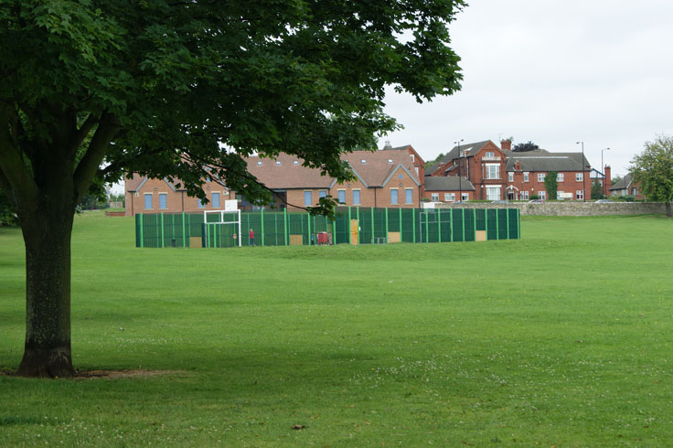 A multi-use games area with some houses behind it.